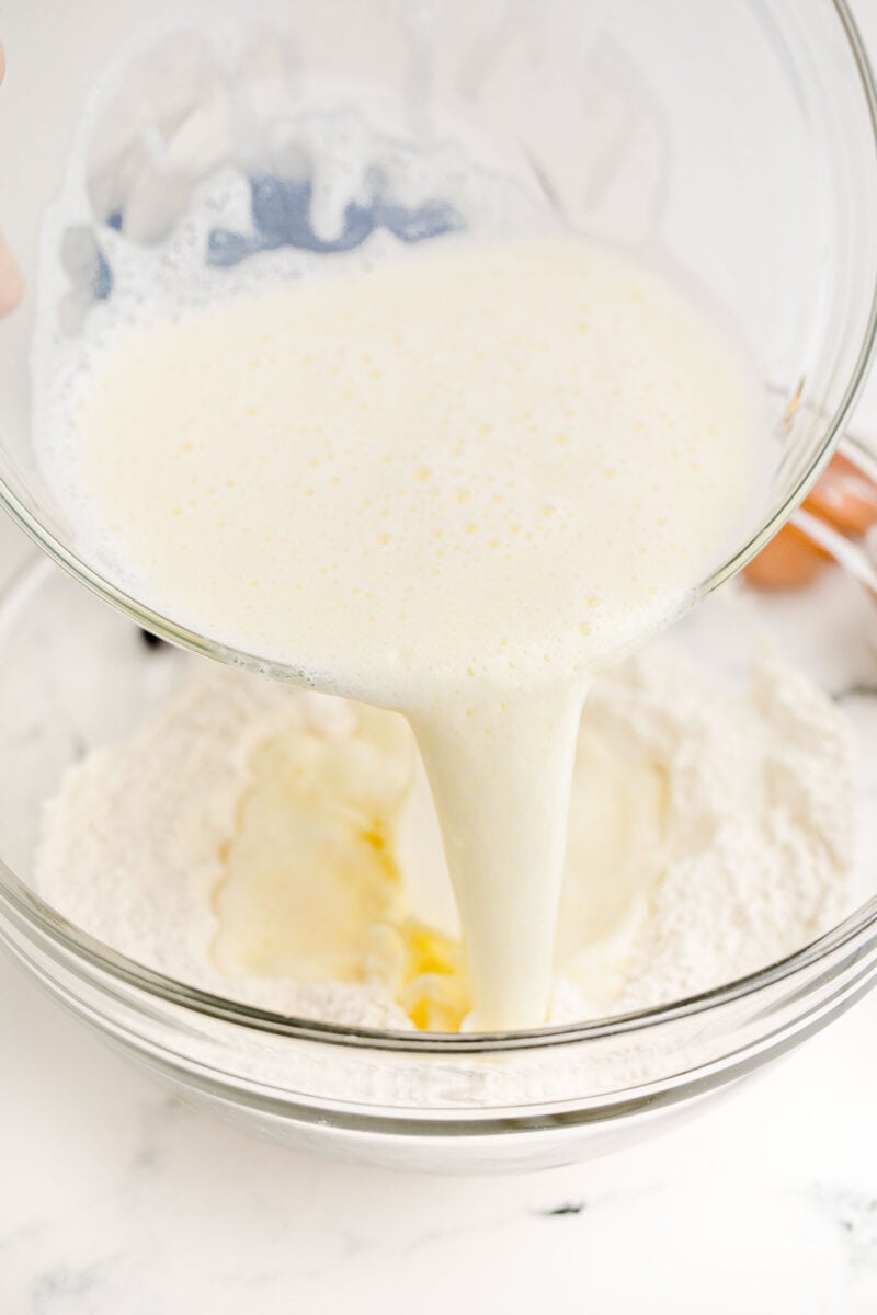 milk is being poured into a bowl filled with dry ingredients.