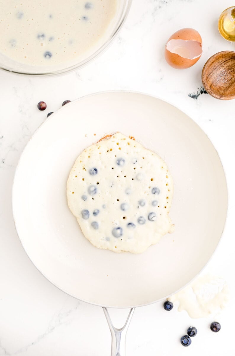 a pancake is being cooked in a large white skillet.