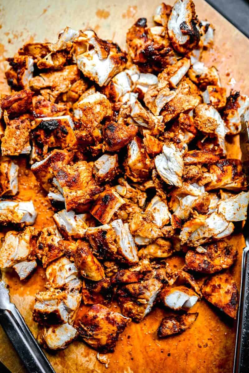 a cutting board is topped with grilled, chopped chicken thighs.