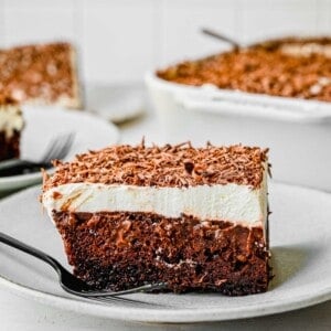 a side view of the chocolate pudding cake. the center is gooey and a black fork can be seen on the white plate with the cake