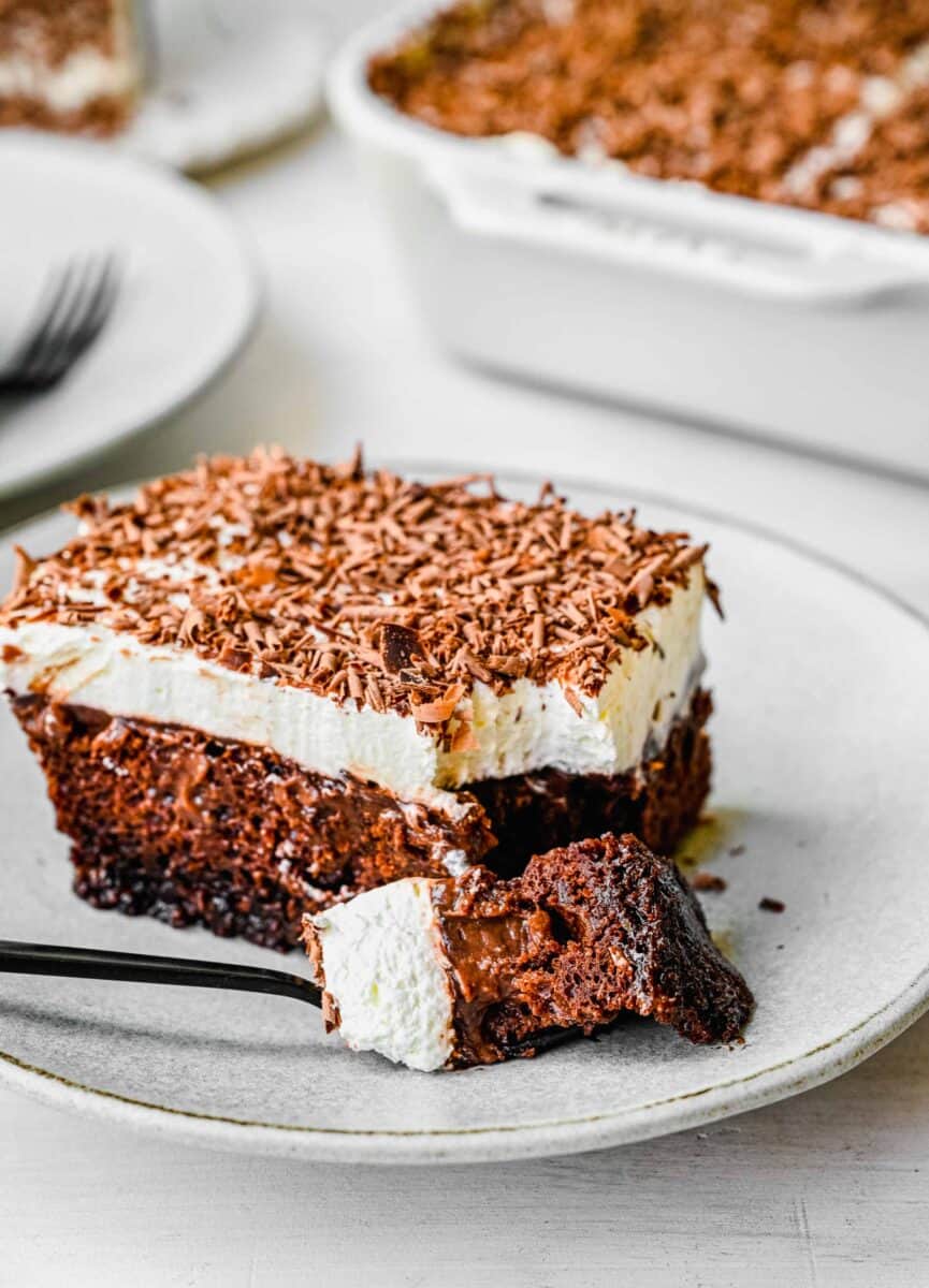 a corner piece of chocolate pudding cake broken off by a black fork on a white plate