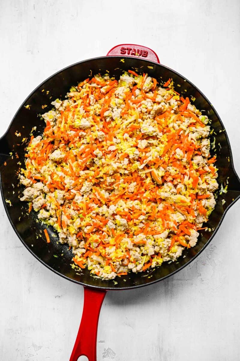 Filling for crispy golden spring rolls; browned ground chicken in a pan with veggies.