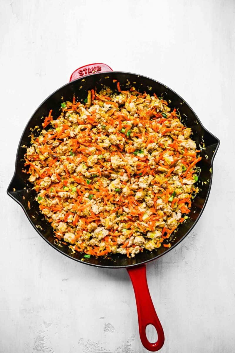 Filling for crispy golden spring rolls; browned ground chicken in a pan with veggies.