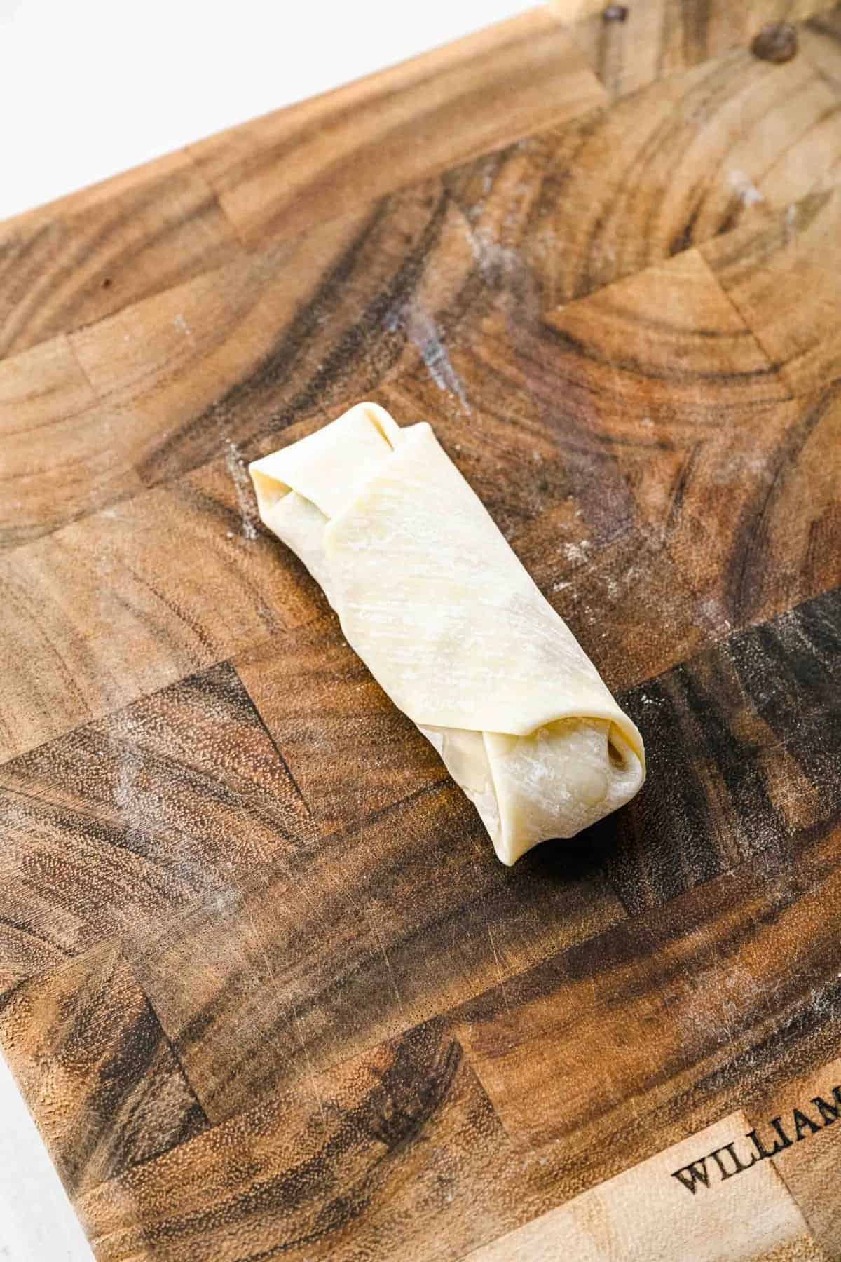 A crispy golden spring roll ready to be fried.