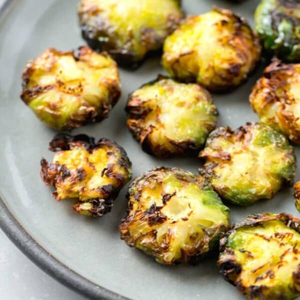 crispy and browned edged smashed brussels sprouts on a grey ceramic plate