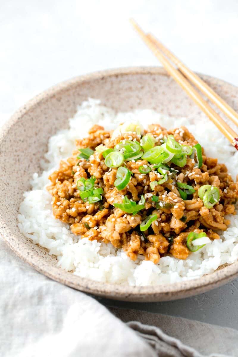 ground chicken teriyaki in a speckled brown bowl on top of white rice