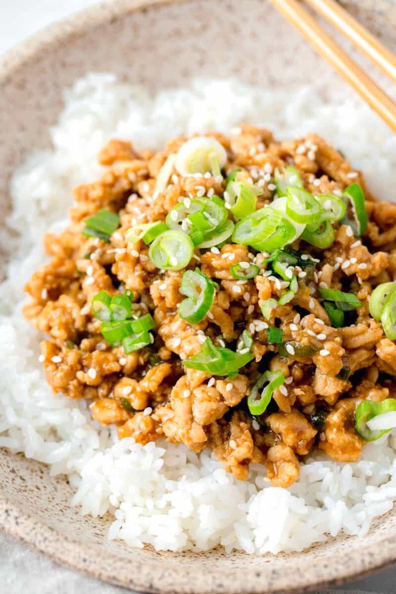 ground chicken teriyaki in a speckled brown bowl on top of white rice