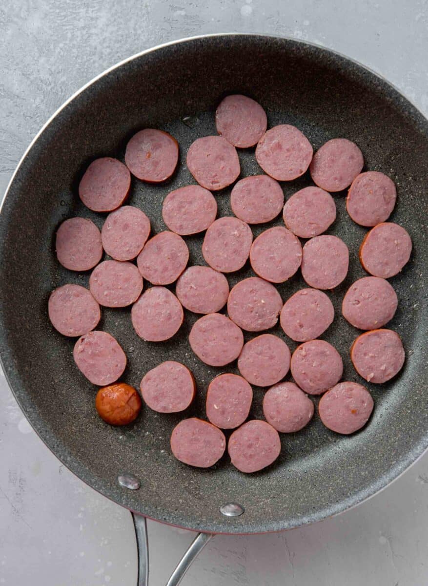 sausage rounds in a grey nonstick skillet