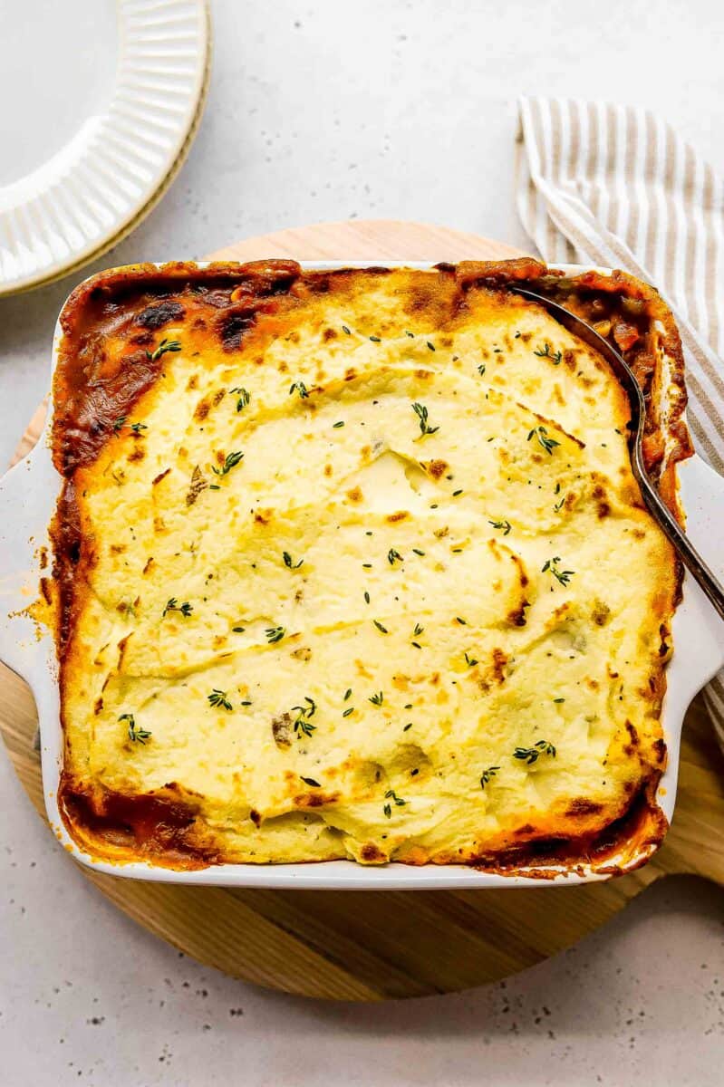 a square white casserole dish is filled with shepherds pie.