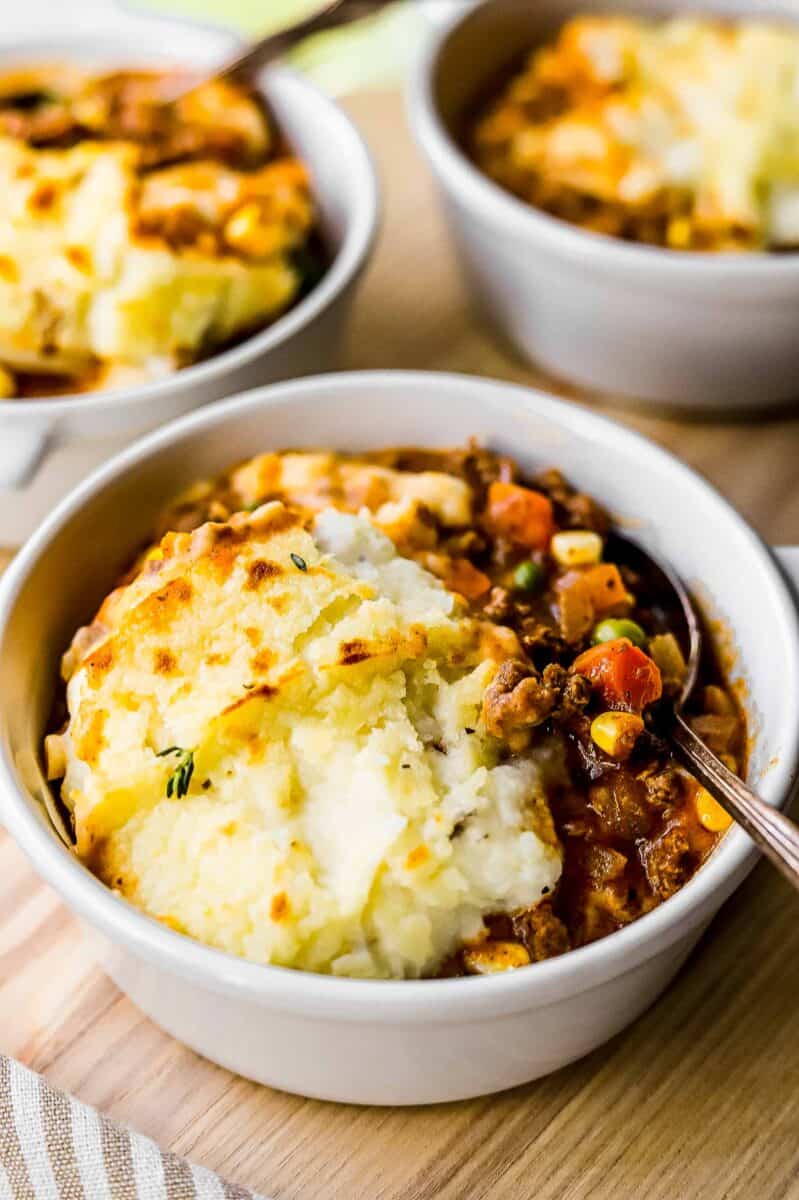 shepherd's pie is placed in a white bowl with a silver spoon.