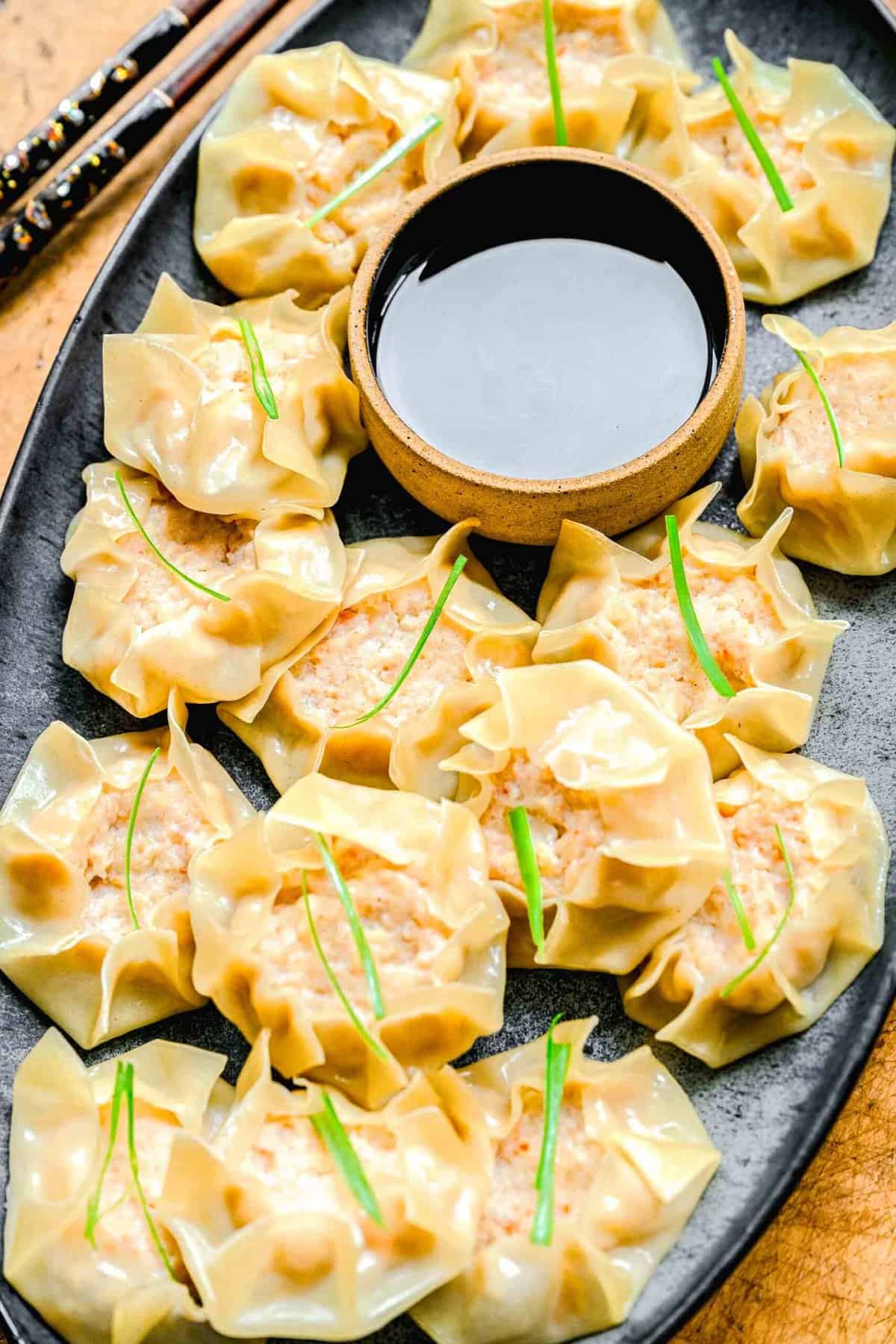 Shrimp shumai on a plate with soy sauce.