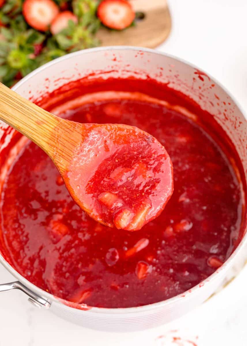 strawberry reduction in a small saucepan and on a wooden spoon