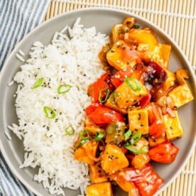 tofu, veggies, and rice are presented together on a single round plate.