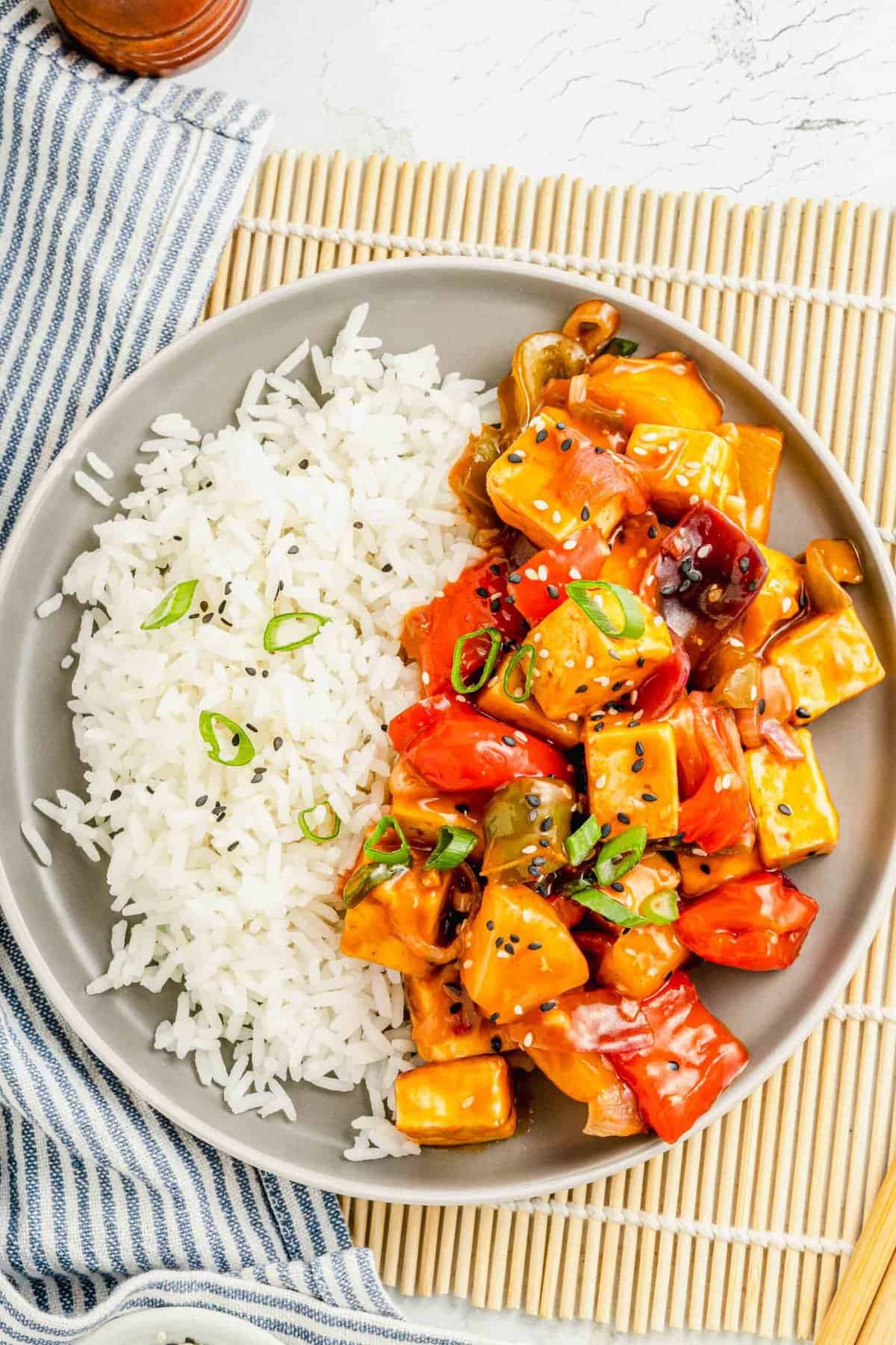 Tofu, veggies, and rice are presented together on a single round plate.