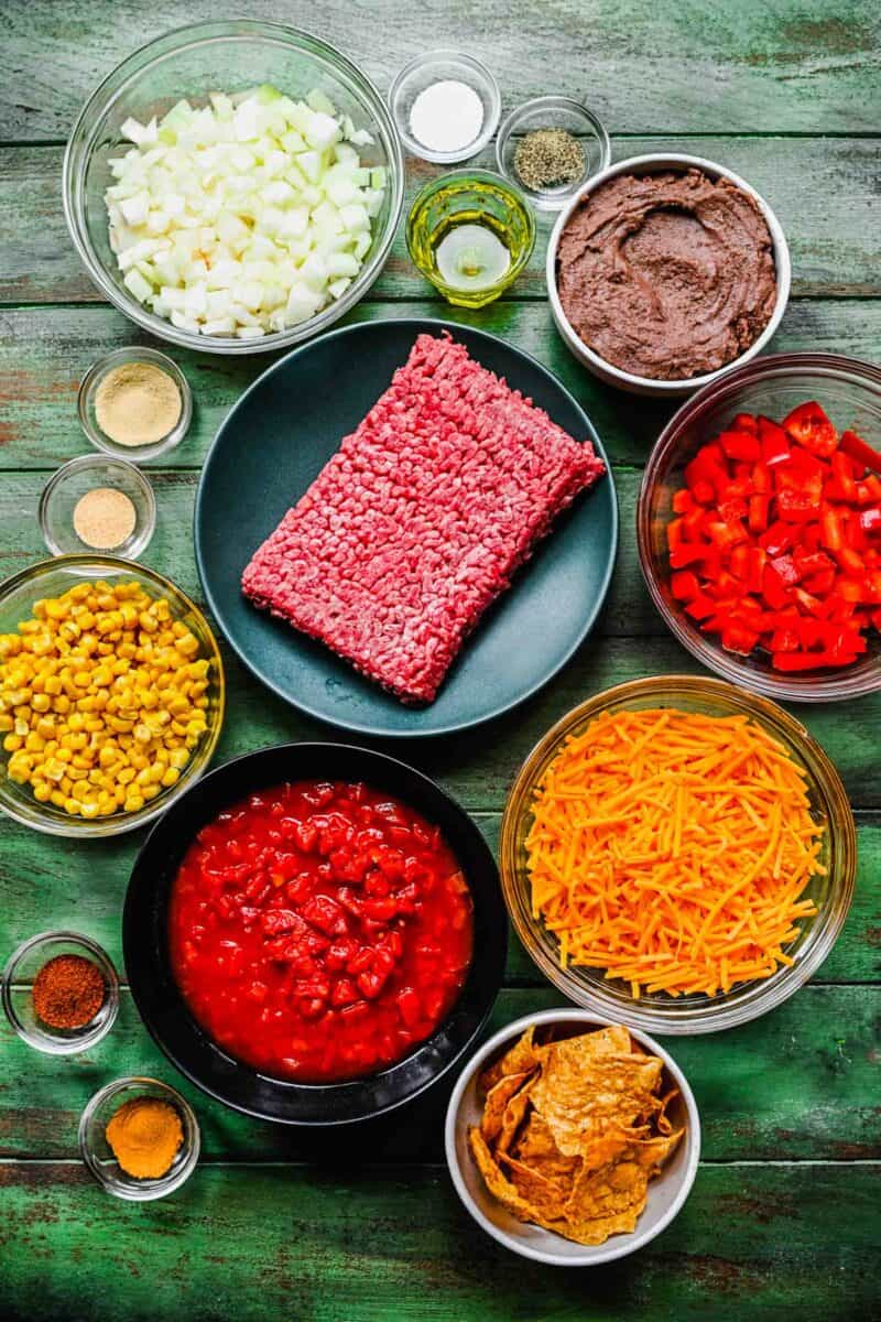 the ingredients for taco casserole are presented on a green surface.