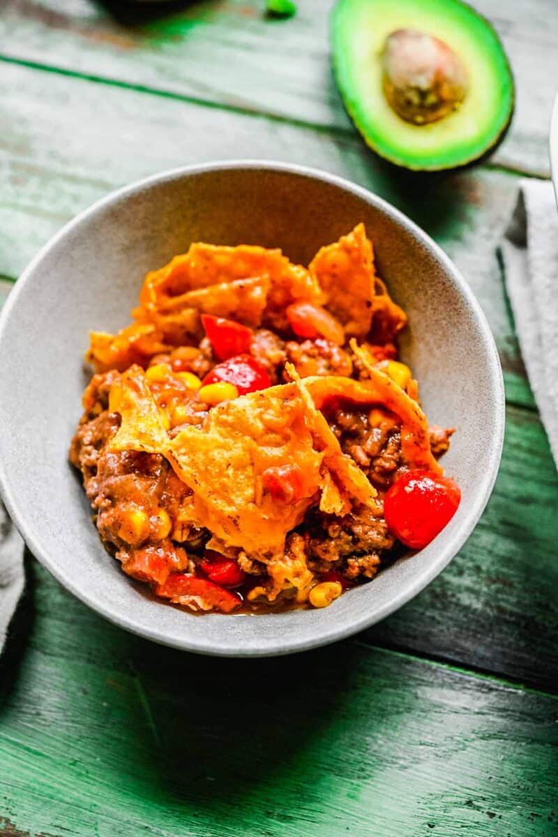 taco casserole in a small bowl with an avocado next to the bowl