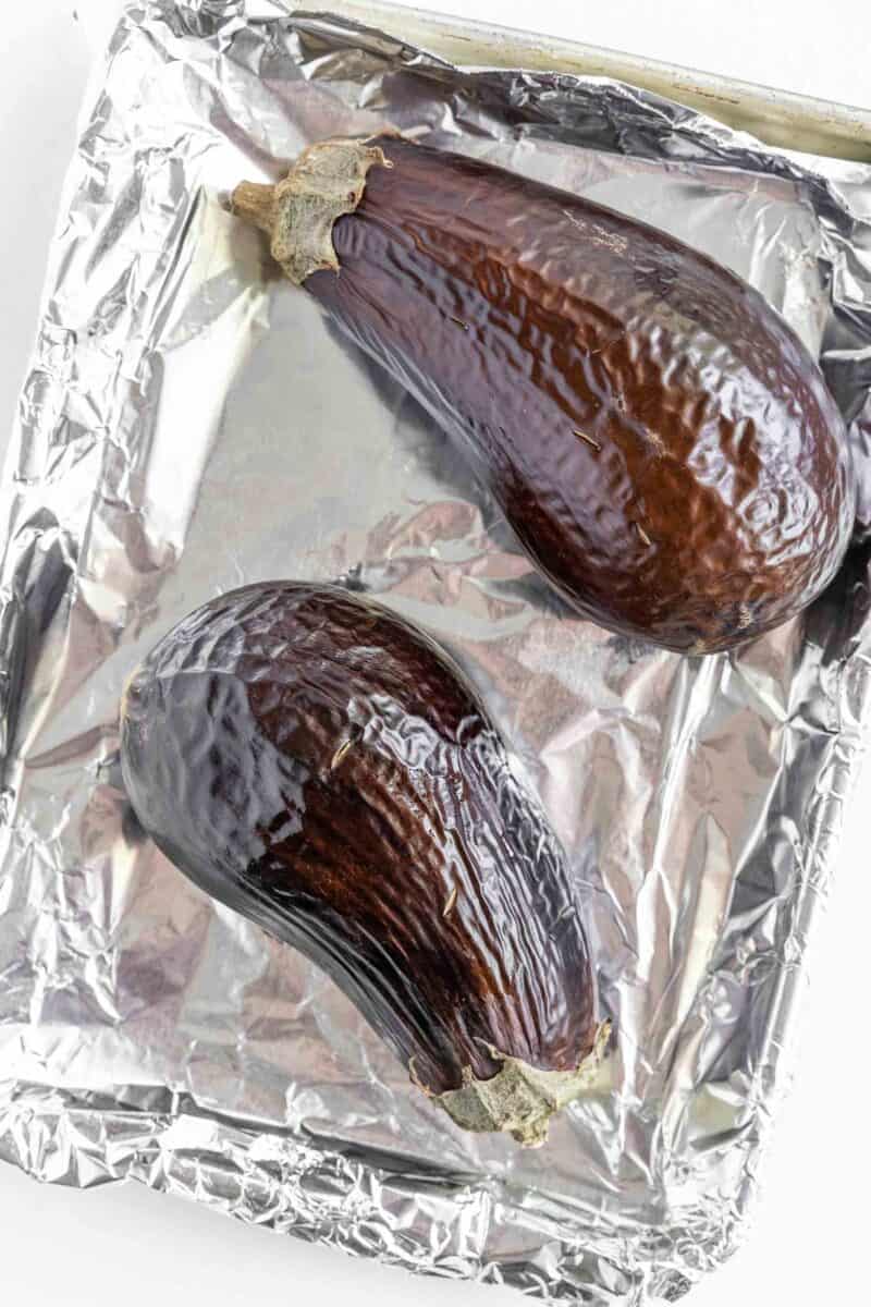 two roasted eggplants are placed on a baking sheet.