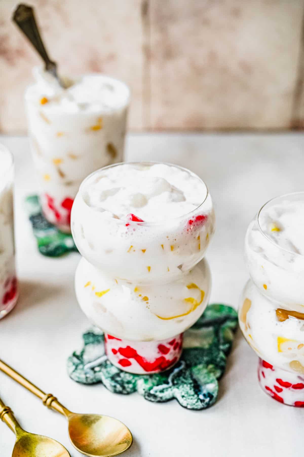 Packed with tropical fruits and crunchy, bright red water chestnuts, this Vietnamese fruit cocktail is the perfect refreshing dessert. Chè Thái in glasses with spoons.