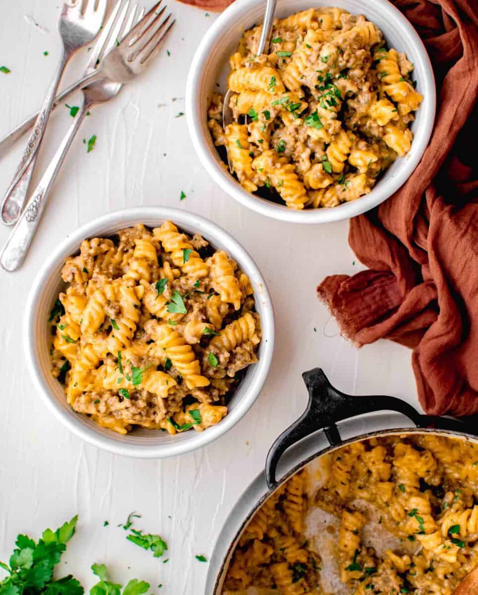 two servings of pasta are placed next to a full pot.