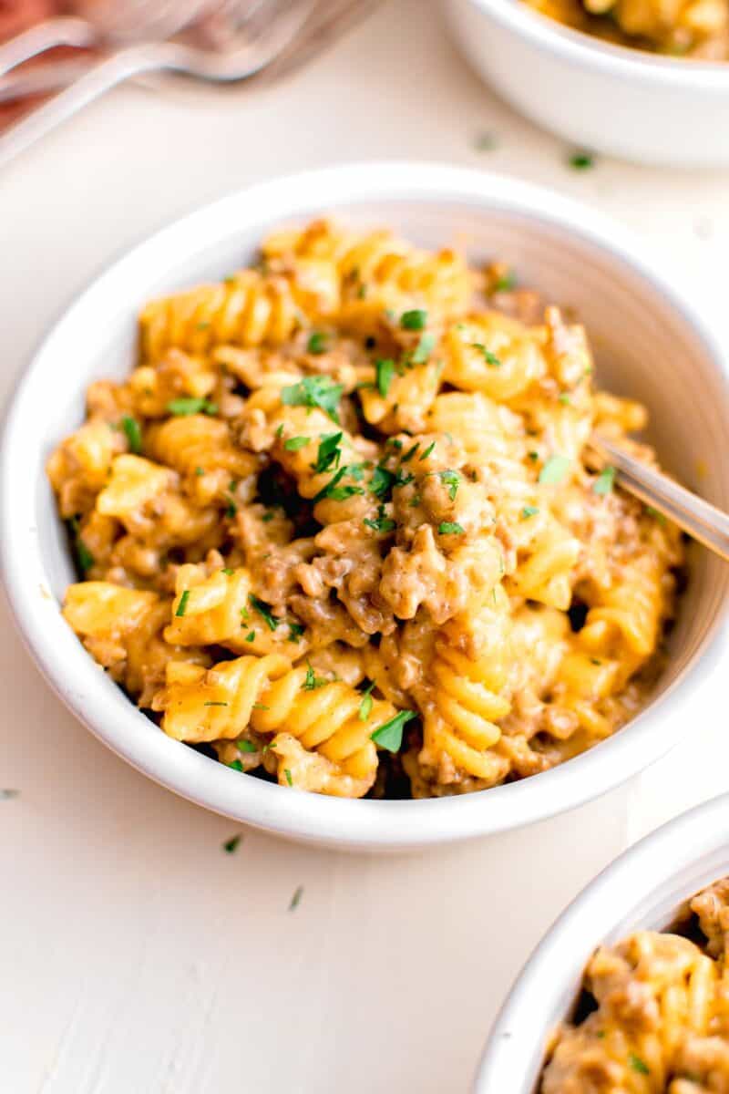 a white bowl is filled with a single serving of cheeseburger pasta.