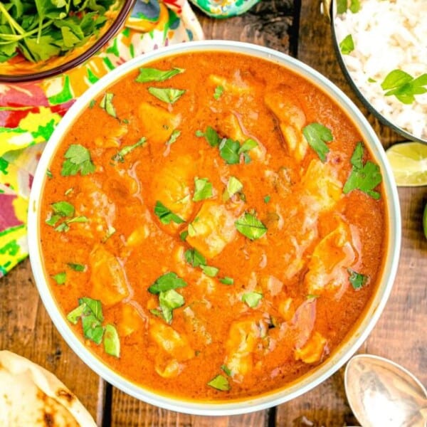 a white bowl is filled with butter chicken.