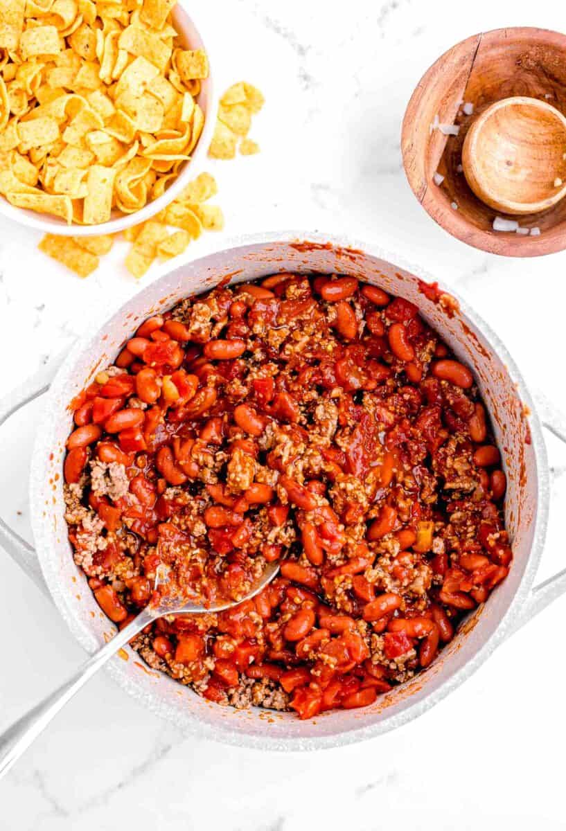 chili is being stirred together with a large spoon in a pot.