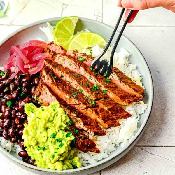 Garlic guajillo steak in a burrito bowl with a fork digging in.