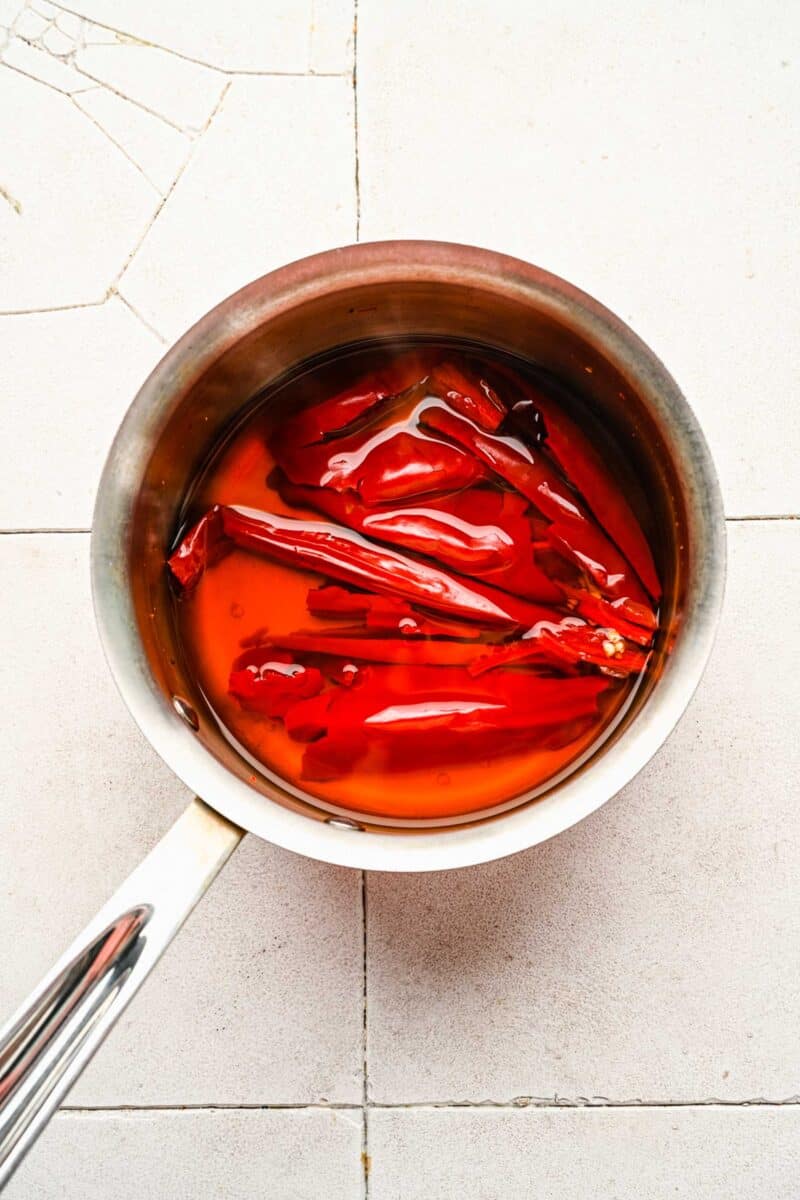 Rehydrating guajillo peppers in a pot.