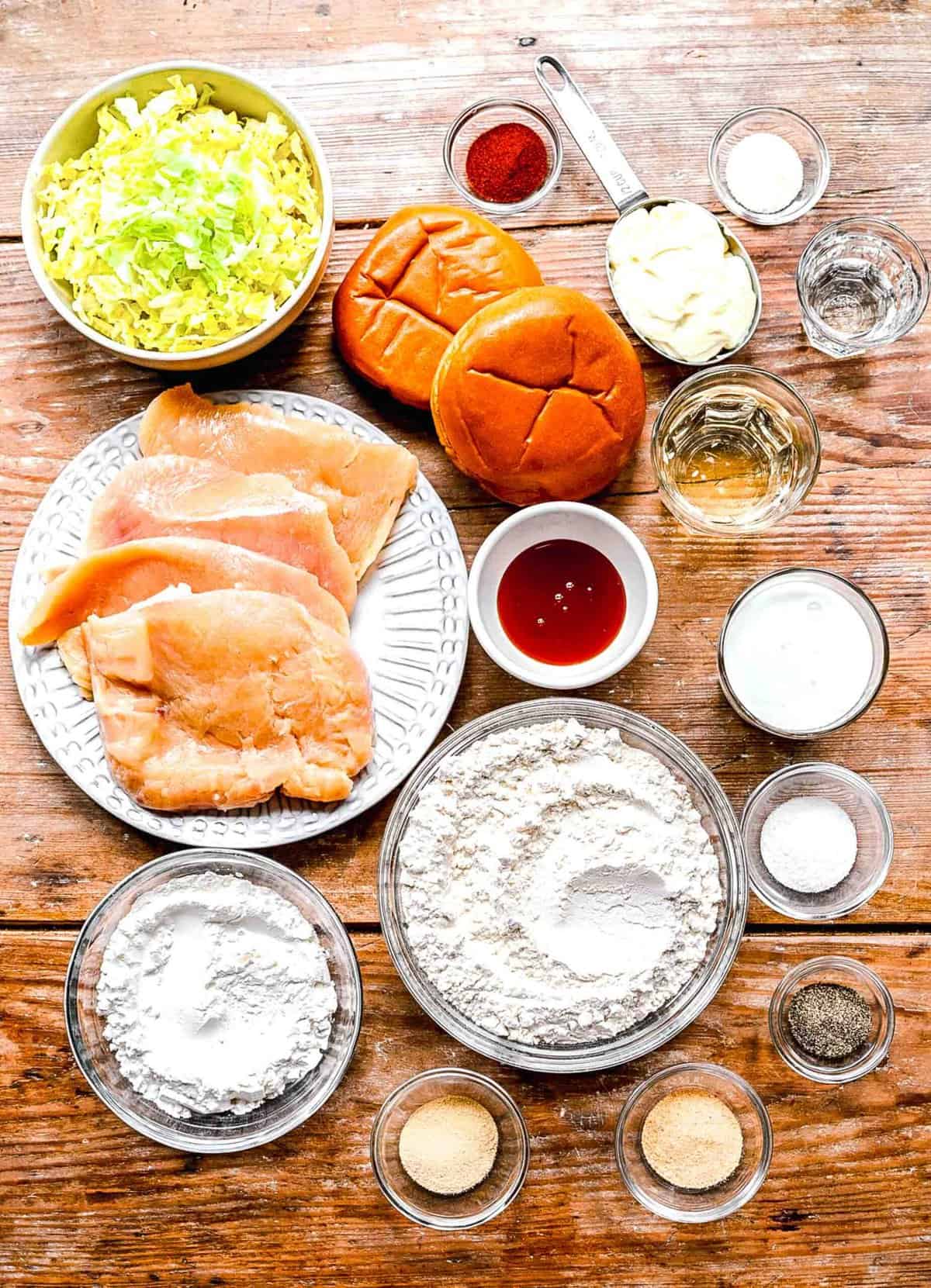 Ingredients for hot honey chicken sandwiches seperated into individual plates and bowl.