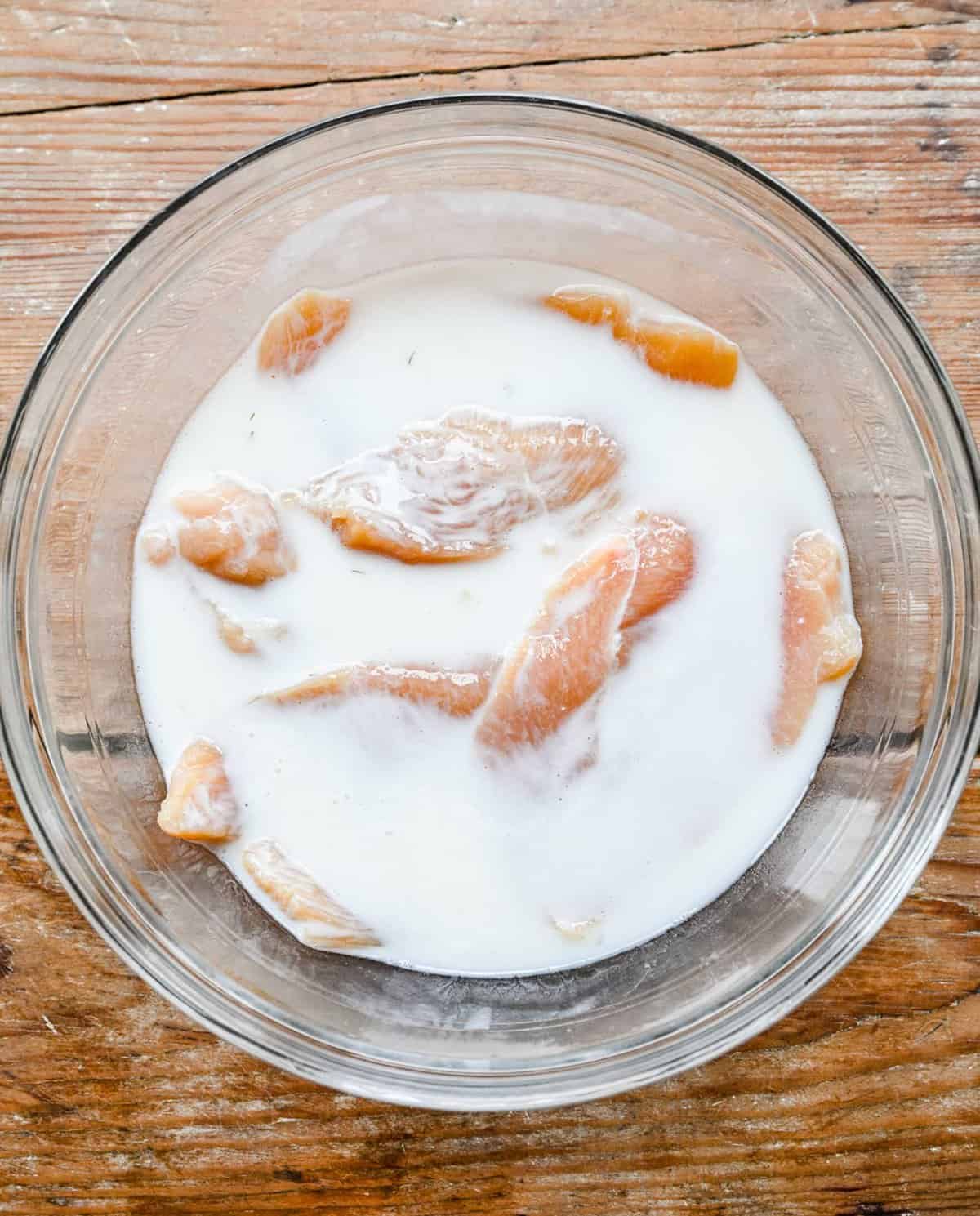 Marinading chicken breasts in a buttermilk mixture.