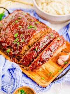 a sliced meatloaf is placed on a wooden serving plate.