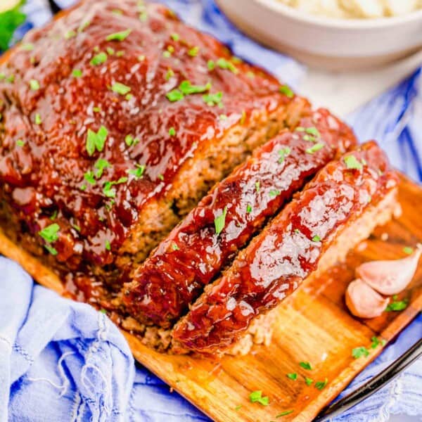 a sliced meatloaf is placed on a wooden serving plate.
