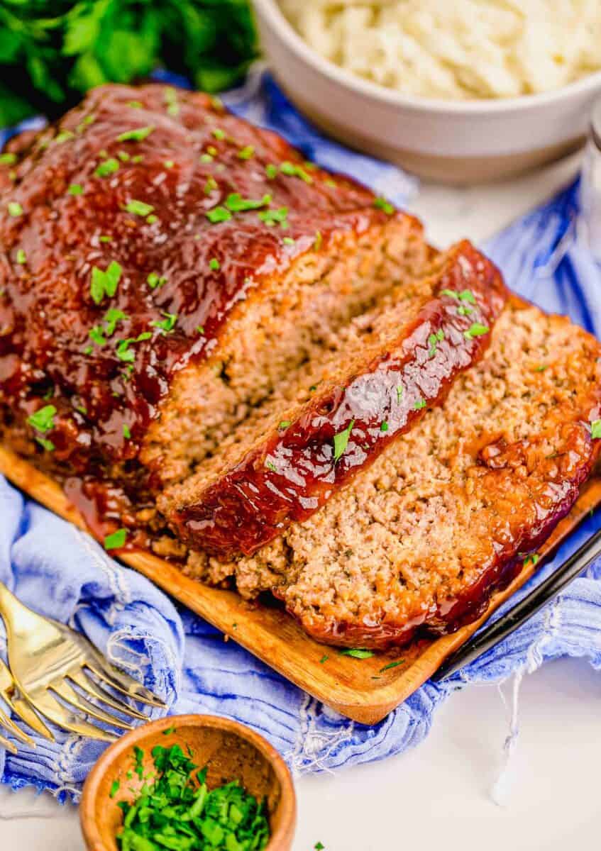 a sliced meatloaf on a serving plate is garnished with fresh parsley.