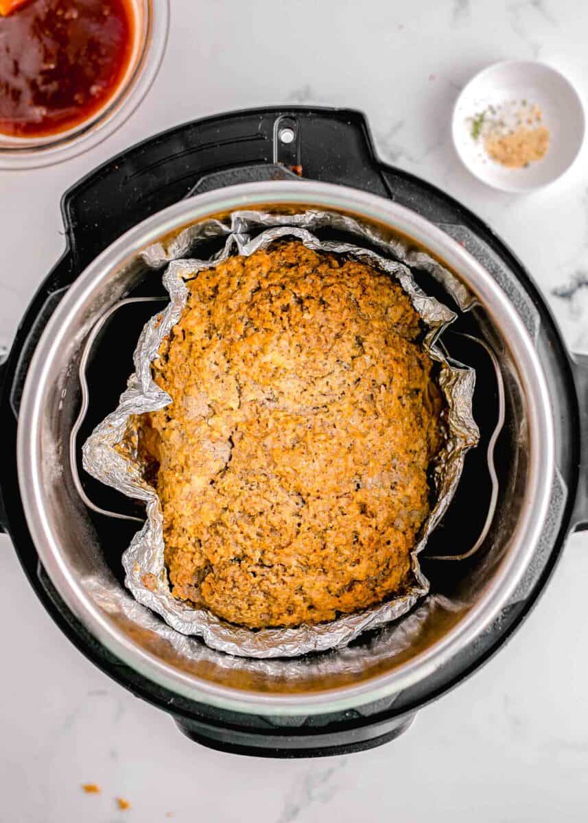 a cooked meatloaf is shown in an instant pot.