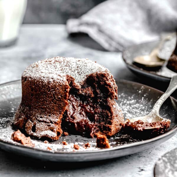 Molten lava cake served on a plates with a spoon near a glass of milk.