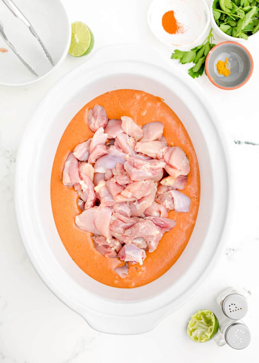 uncooked chicken is placed in the center of a slow cooker.