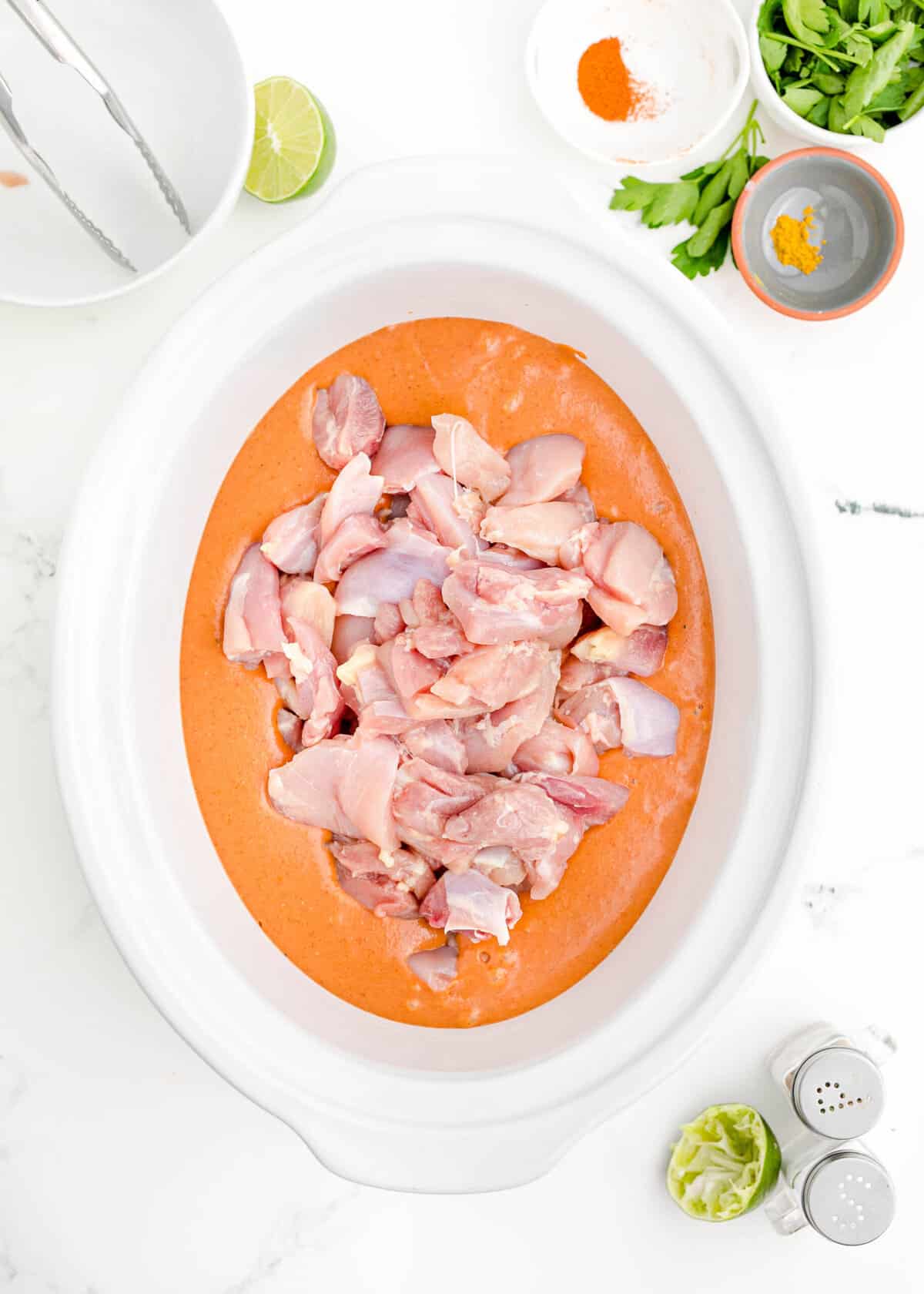 uncooked chicken is placed in the center of a slow cooker.