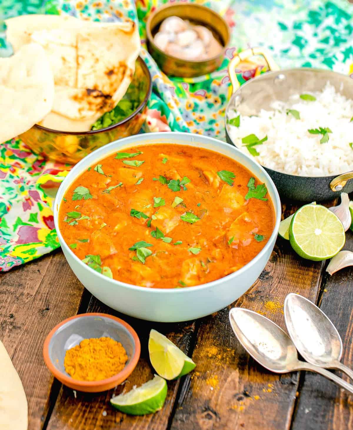 a bowl filled with butter chicken is garnished with fresh greens.