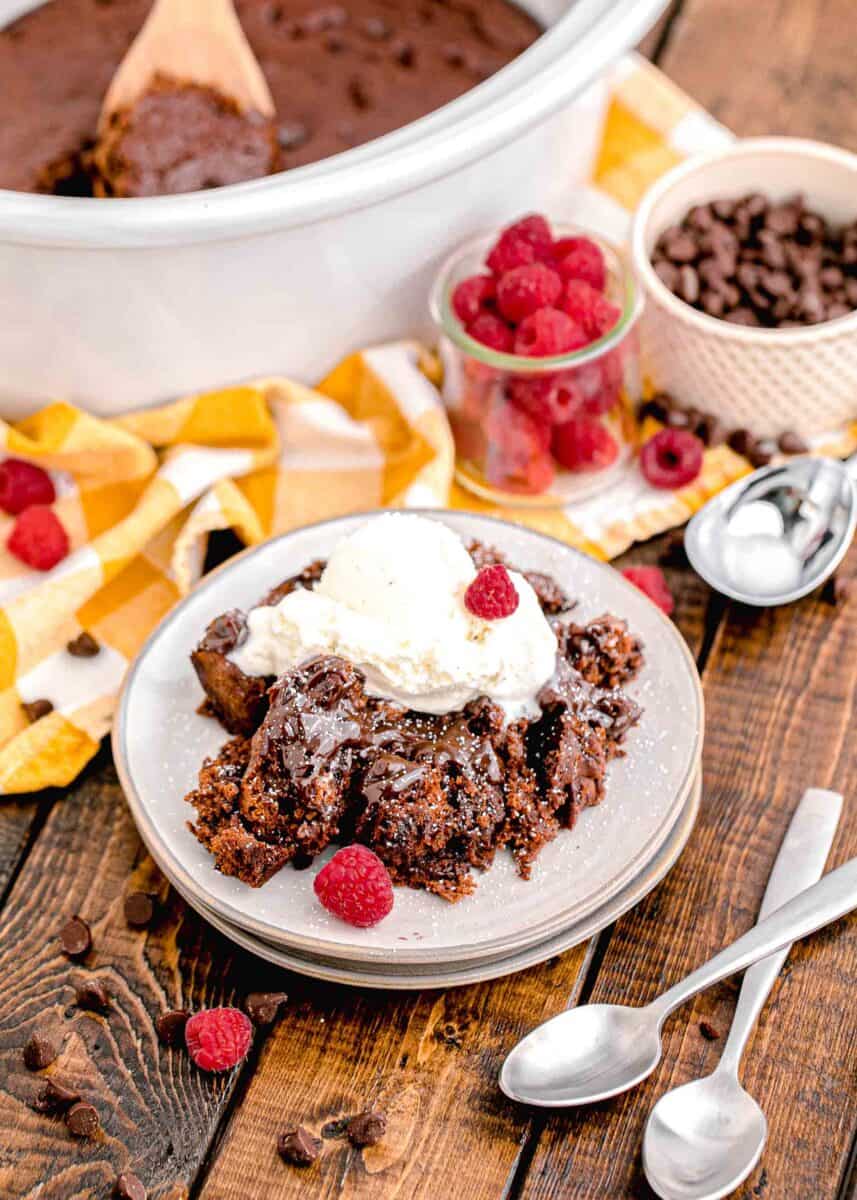 a serving of chocolate cake is plated and topped with whipped cream and berries.