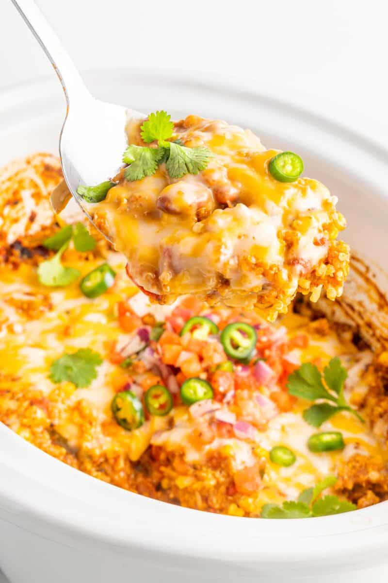 a spoon is lifting a portion of casserole out of the Crockpot.