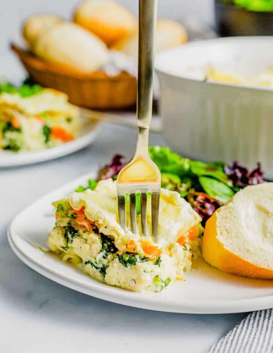 a fork is piercing a serving of lasagna on a plate.