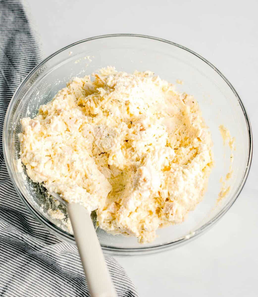 a glass mixing bowl container a cheesy egg mixture.