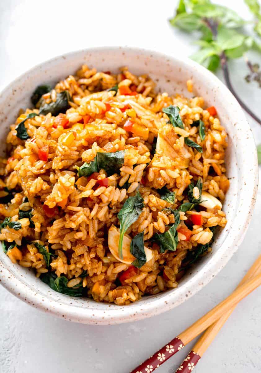 thai basil fried rice in a speckled ceramic bowl next to wooden chopsticks