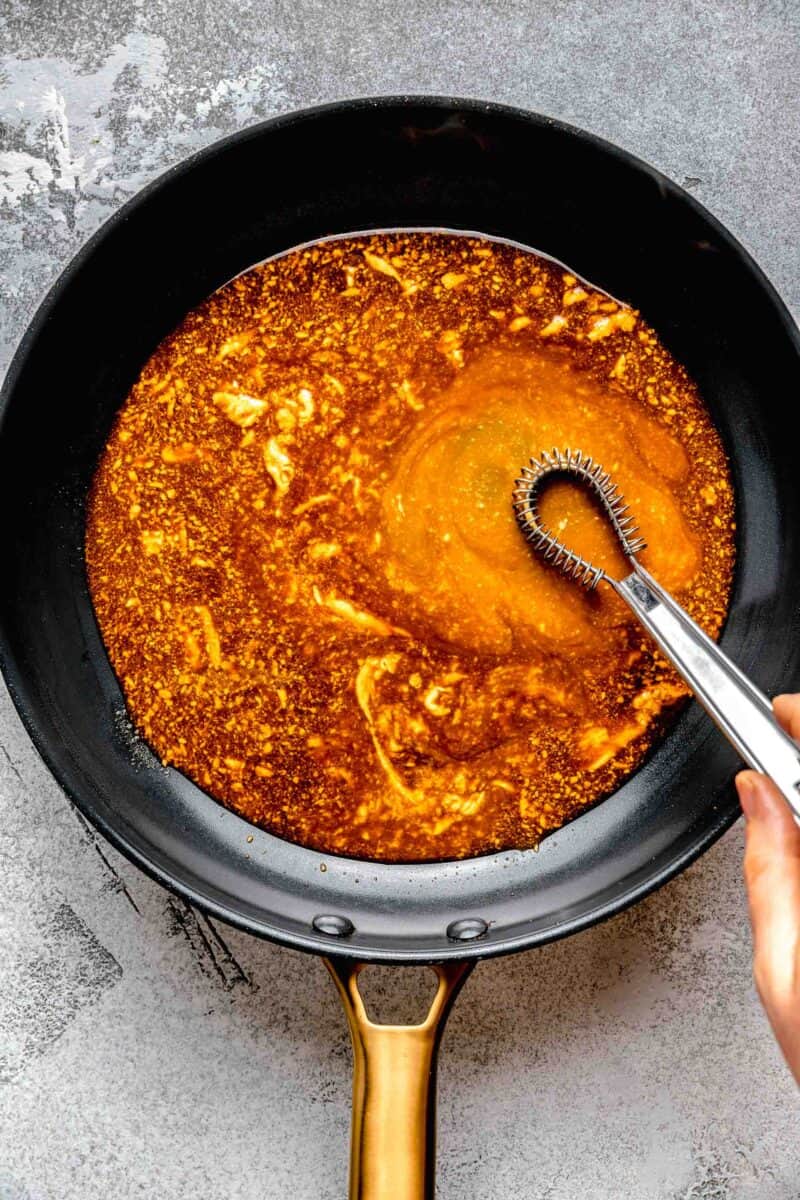 Whisking butter into sauce in a pan.