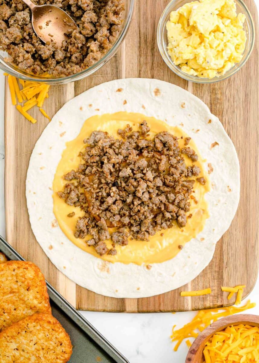 cheese and sausage are placed on top of a tortilla.