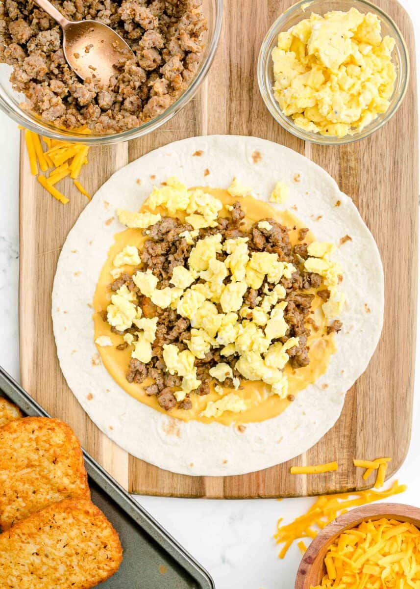 a tortilla is topped with eggs, cheese, and sausage.