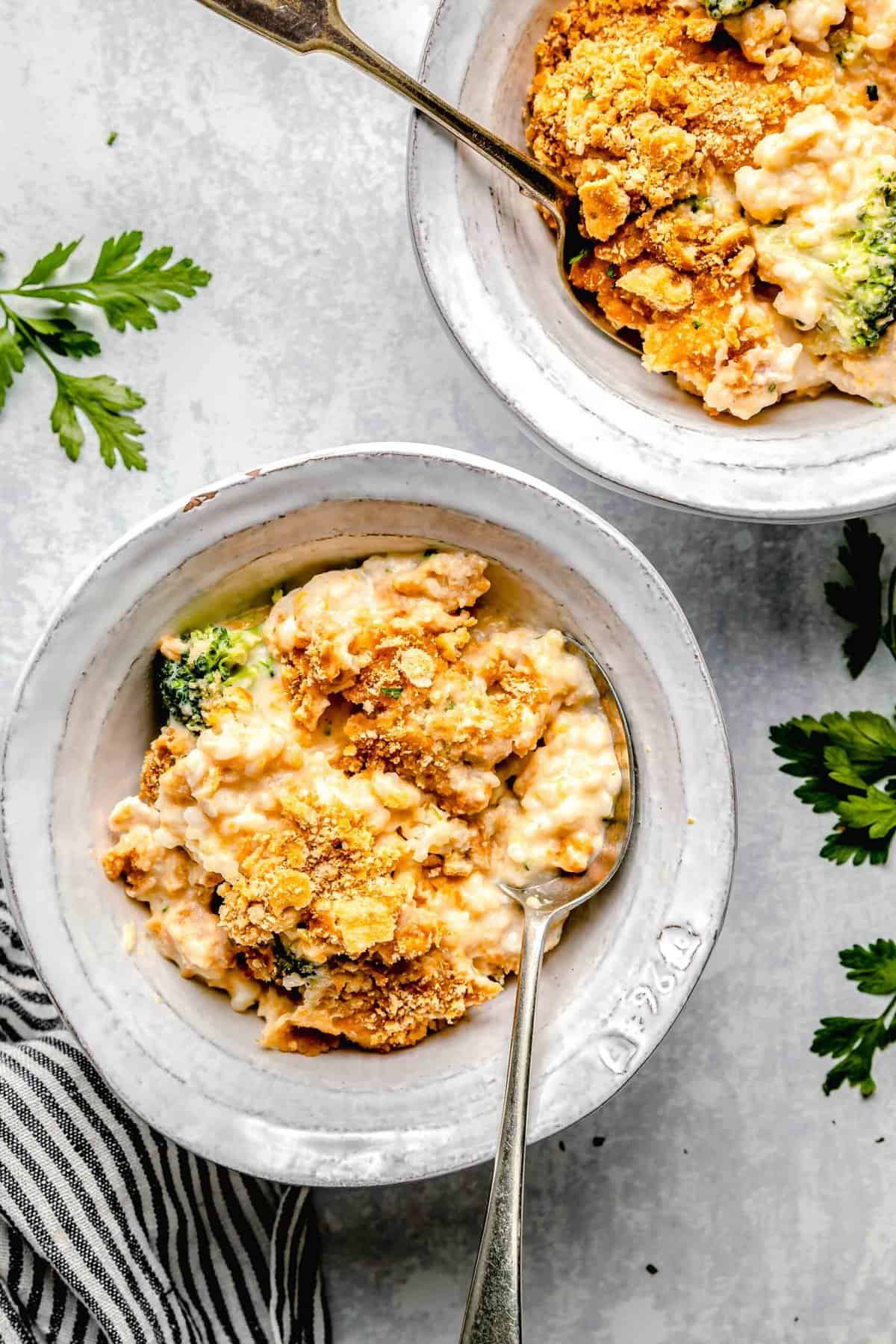 This cheesy chicken broccoli rice casserole is topped with buttery Ritz crackers and comes together so quickly. It's a perfect weeknight meal. Chicken broccoli rice casserole served in bowls with spoons.