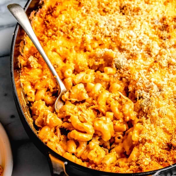 a spoon is placed in a large dish filled with mac and cheese.