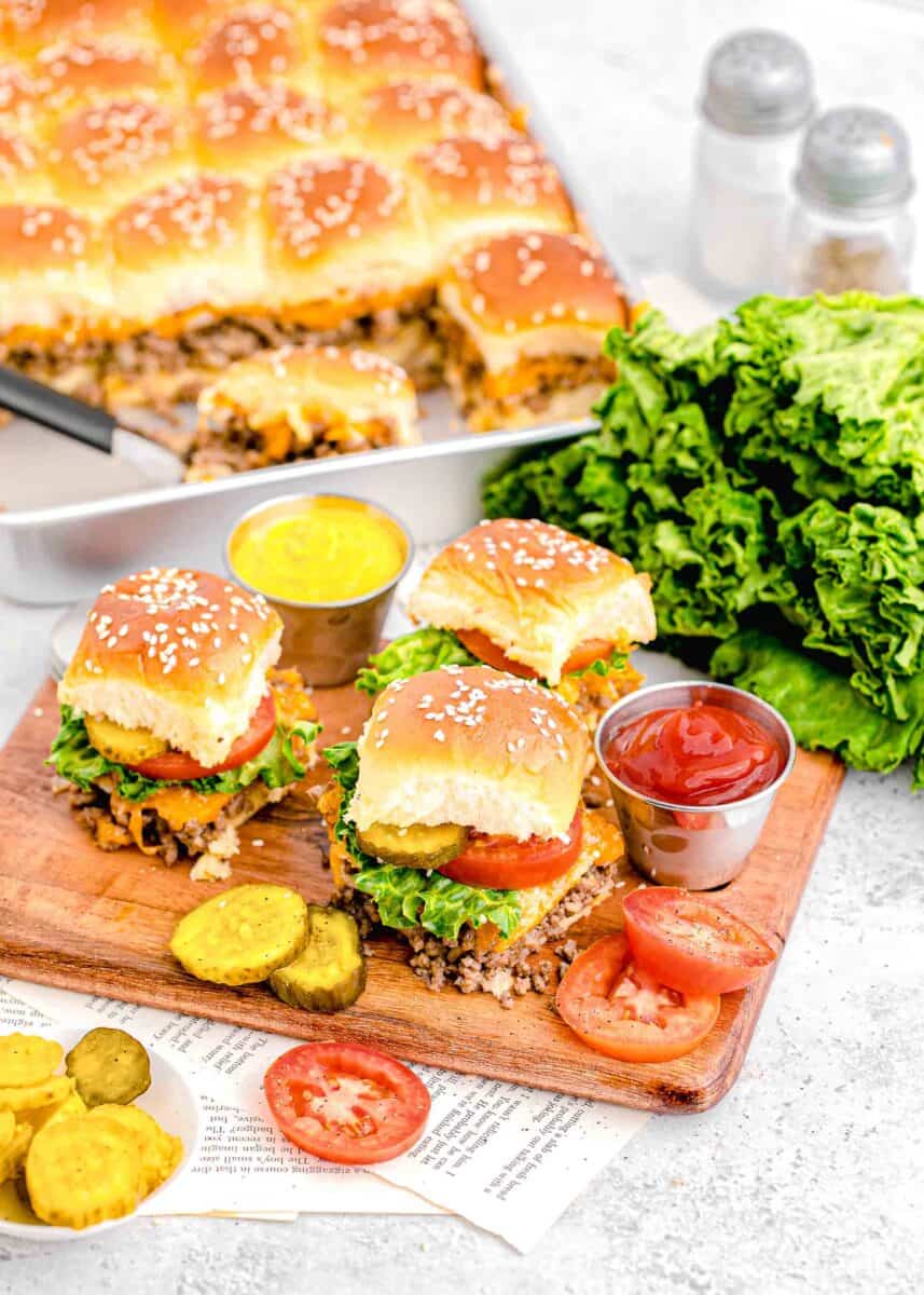 several cheeseburger sliders are placed on a cutting board.