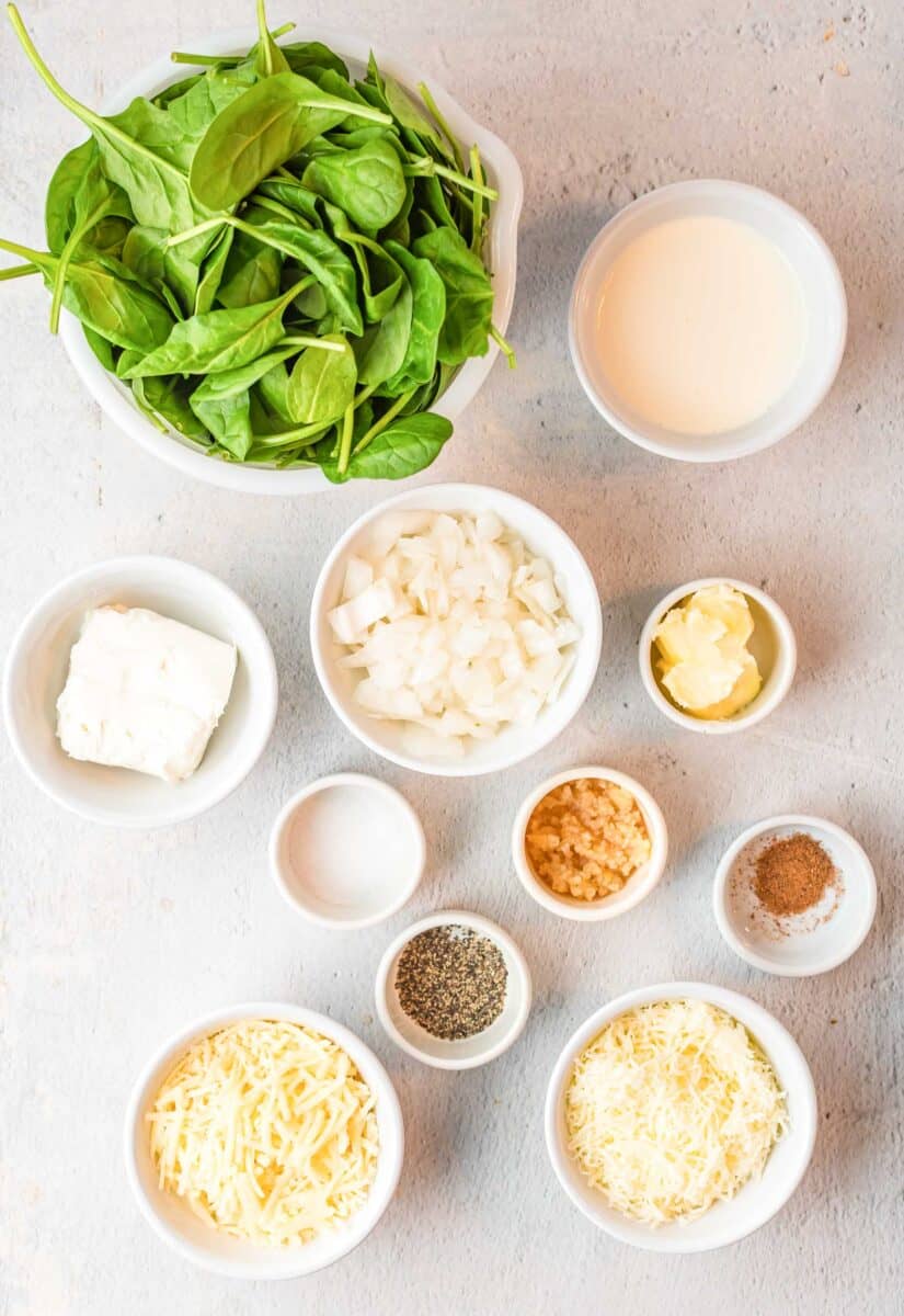 the ingredients for creamed spinach are placed on a white surface.